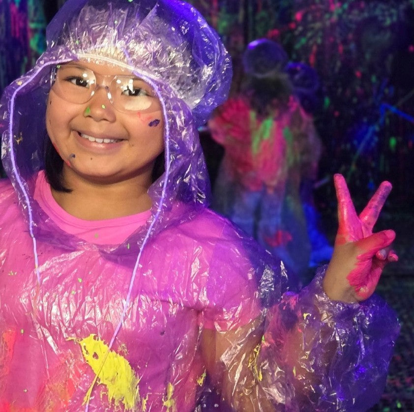 Person wearing a clear raincoat with colorful lights in the background