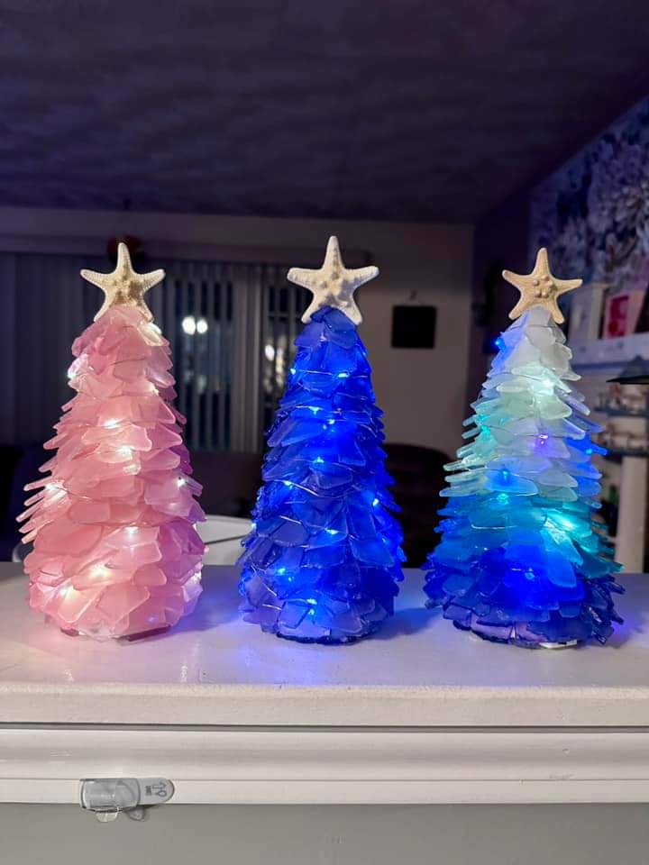 Three decorative Christmas trees with star-shaped ornaments on a surface.