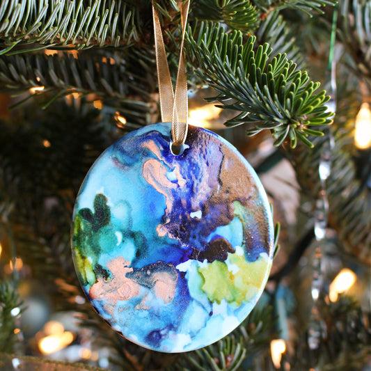Decorative ornament with a colorful design hanging on a Christmas tree.