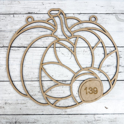Wooden pumpkin-shaped cutout with the number 139 on a white wooden surface