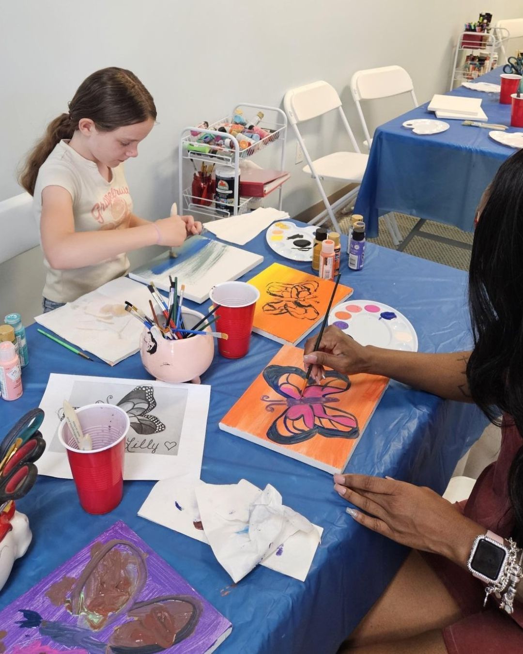 Two children engaged in a painting activity at a table with art supplies.
